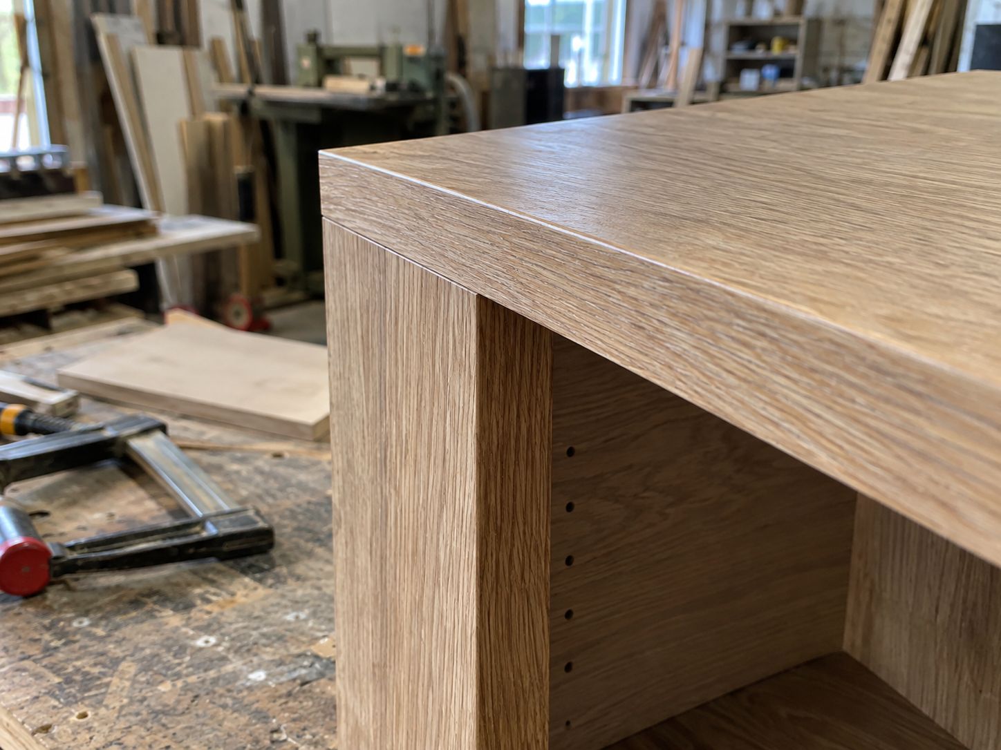Détail d'assemblage d'un meuble sur mesure en atelier : jonction de panneaux et chant.