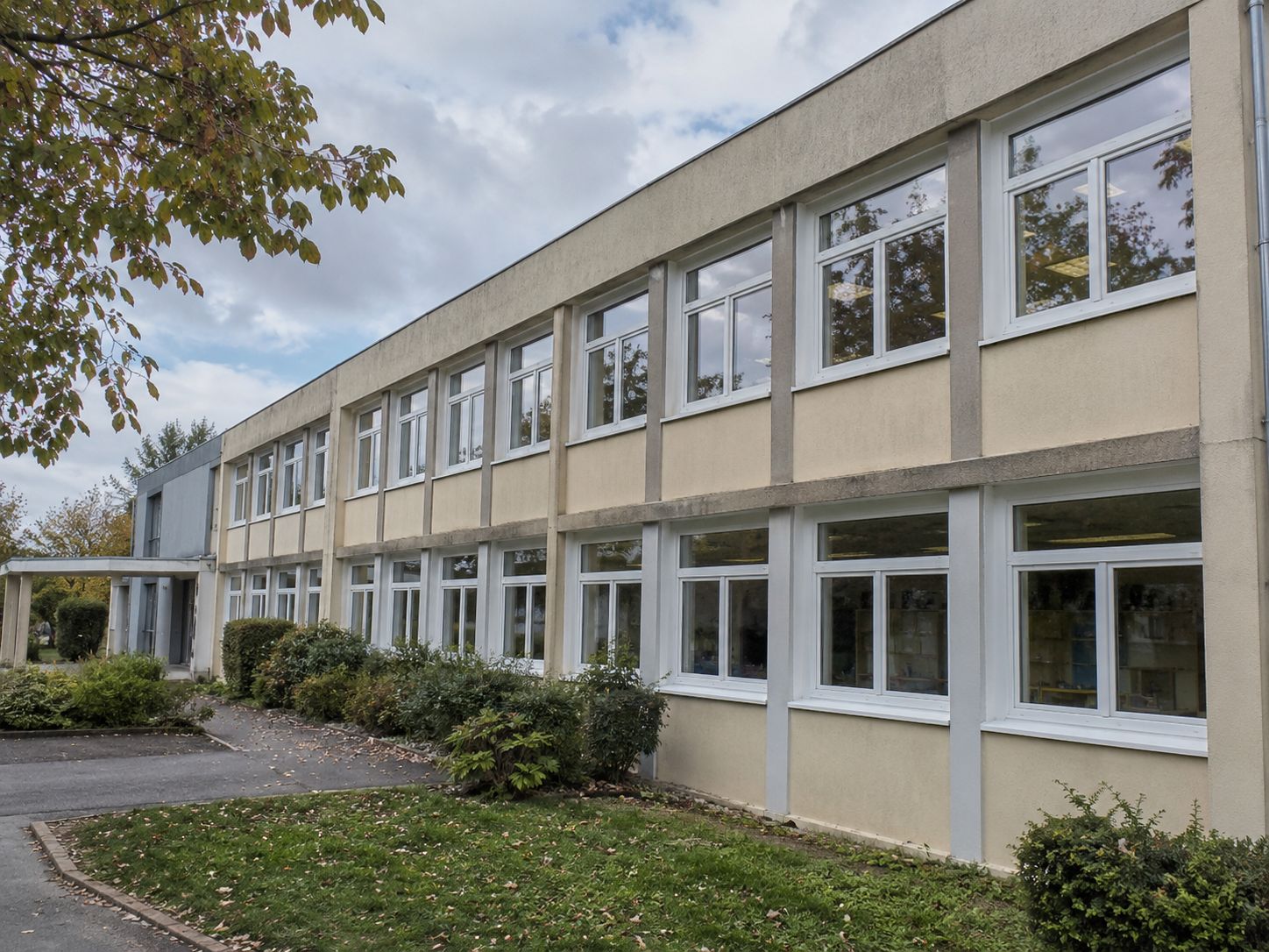 Menuiseries installées sur un bâtiment scolaire : façade rythmée de fenêtres remplacées.
