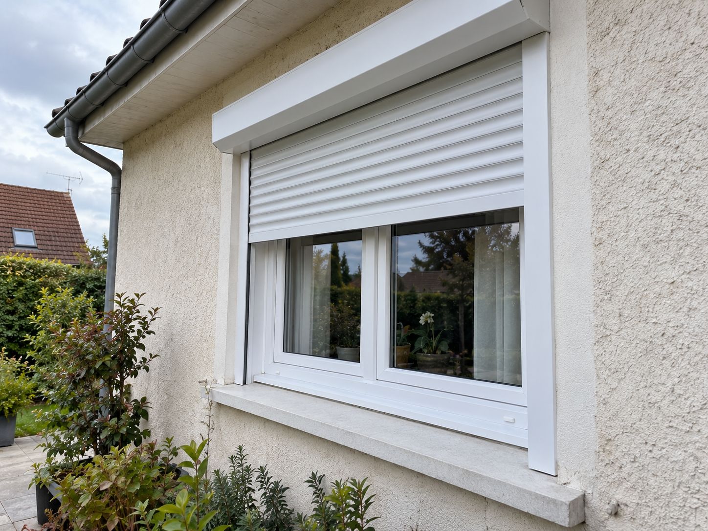 Fenêtre PVC blanche deux vantaux et volet roulant blanc coordonné, vue de façade.