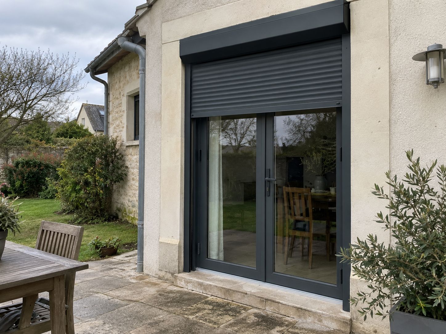 Porte-fenêtre anthracite et volet roulant coordonnés, ouvrant sur une terrasse.